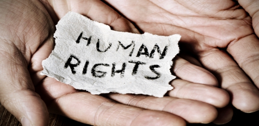 closeup of the hands of a young man with a piece of paper with the text human rights written in it, with a dramatic effect